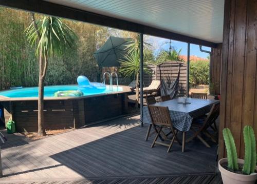 une terrasse avec un bain à remous, une table et des chaises dans l'établissement Jolie maison de vacances proche lac, à La Teste-de-Buch