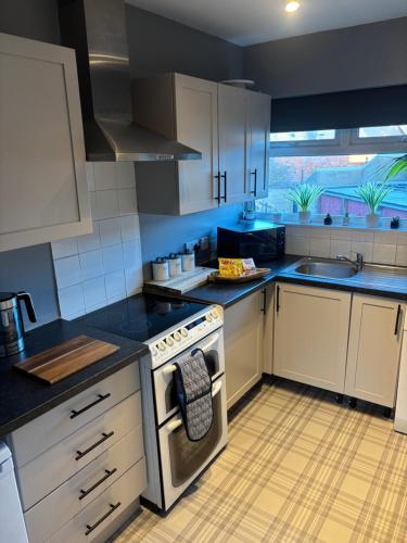 a kitchen with white cabinets and a stove top oven at Fantastic full 3 bedroom modern apartment in Belfast