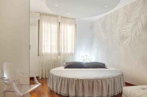 a white bedroom with a bed and a chair at Casa Louise - appartamento Don Bedetti in Bologna