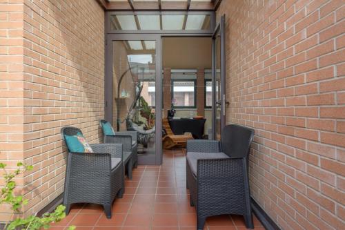 a patio with wicker chairs and a brick wall at Casa Louise - appartamento Don Bedetti in Bologna