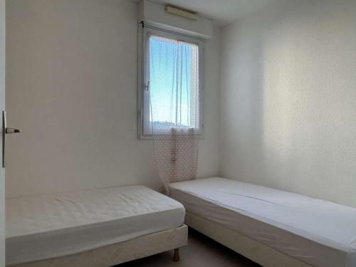 deux lits dans une petite pièce avec une fenêtre dans l'établissement Appart 2 pièces 4 couchages BANYULS SUR MER BN120-4114, à Banyuls-sur-Mer