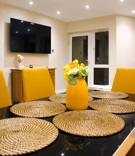 a dining room table with yellow chairs and a vase with flowers at 2 bed apartment clan house apartments in Galway