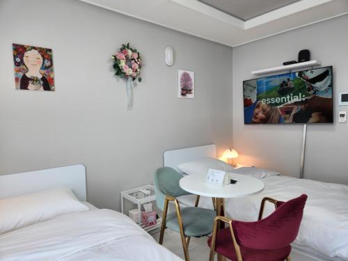 a room with two beds and a table and a tv at Daegu Star B&B DSR Hotel lily in Daegu