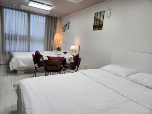 a hotel room with two beds and a table and chairs at Daegu Star B&B DSR Hotel lily in Daegu