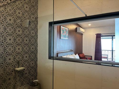 a bathroom with a glass door leading to a bedroom at The Green Gate Resort Mulshi in Pune
