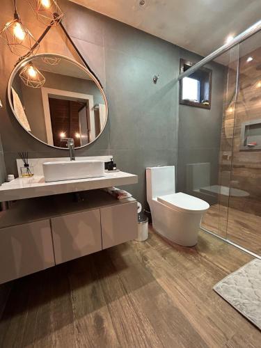a bathroom with a sink and a mirror and a toilet at Chalé Rústico Aconchegante com Hidro in Araranguá