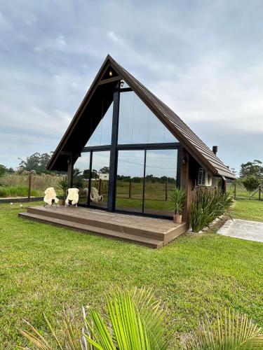 a small house with glass windows on a lawn at Chalé Rústico Aconchegante com Hidro in Araranguá