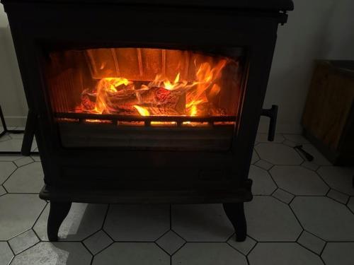 a fireplace with fire in it on a tiled floor at Boshuisje in Couvin