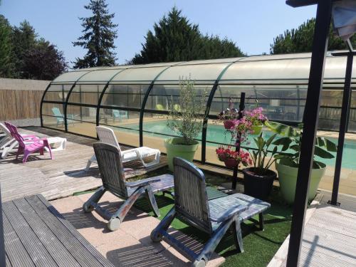 a patio with three chairs and a swimming pool at chalet ESPAGNE pour 2 personnes in Chazemais
