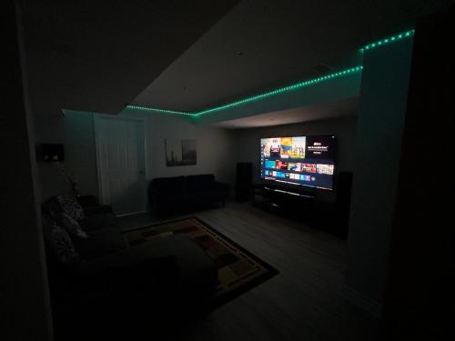 a dark living room with a flat screen tv at Ravine Retreat - 3RM Suite, 2BD, 1 WR, Pool, Sauna in Whitby