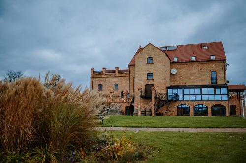 a large brick building on a grass field at Folwark Pszczew in Pszczew