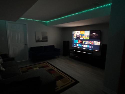 a living room with a large flat screen tv at Ravine Retreat - 3RM Suite, 2BD, 1 WR, Pool, Sauna in Whitby