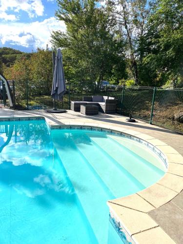 une grande piscine bleue avec un parasol dans l'établissement La Riviere Esperance, à Veyrignac