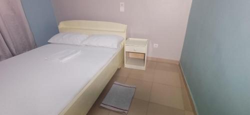 a small bedroom with a white bed and a night stand at Residence MaryHouse - Free Breakfast and Taxi From Airport in Cotonou