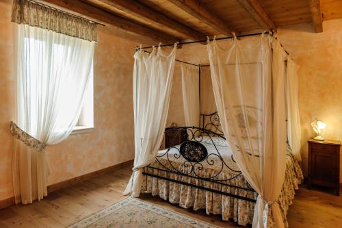 a bedroom with a canopy bed and two windows at Cascina Le Preseglie in Desenzano del Garda
