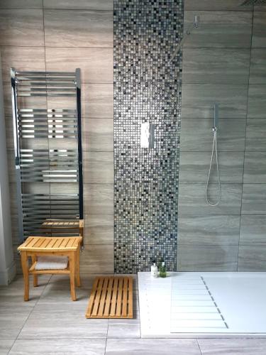 a bathroom with a shower and a bench and a tub at Tranquil & Unique Villa on the UK's sunniest place in Ratton Village