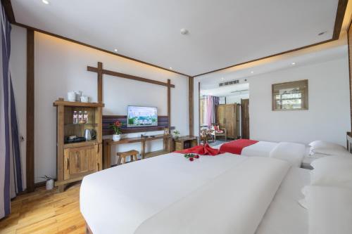 a bedroom with a large white bed and a tv at 云海酒店 in Zhangjiajie