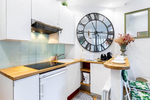 une cuisine avec une grande horloge murale dans l'établissement GuestReady - Unwind in Style in the heart of Paris, à Paris