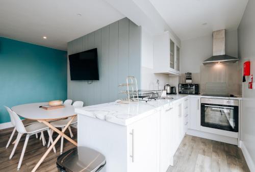 a kitchen with white cabinets and a table and chairs at Cliff Cottage - Luxurious Seaview Retreat in Gorleston-on-Sea