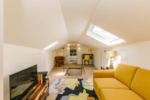a living room with a yellow couch and a tv at Bairro Alto Music Guest House in Lisbon