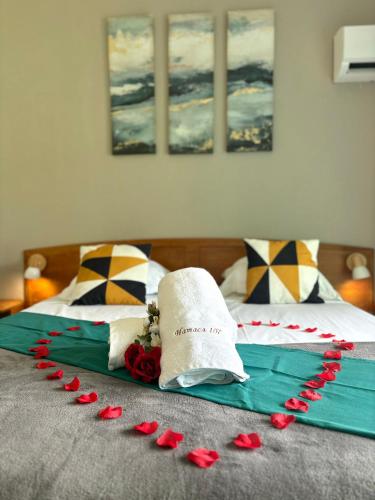 a bed with red rose petals on top of it at La Perle de l'Hamaca - Idéal pour les Couples, Piscine et Plage in Grand-Bourg