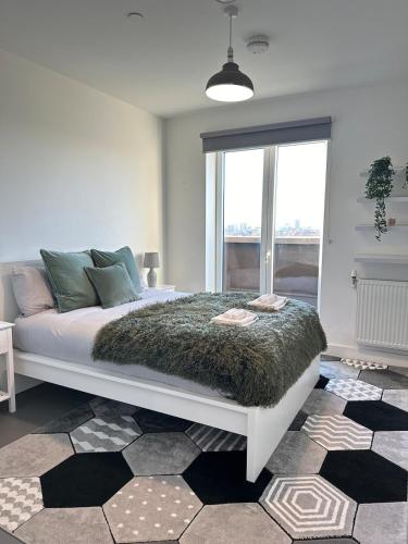 a bedroom with a white bed with a green blanket at Beautiful 1 Bd Top floor Terraced Apartment in Barking
