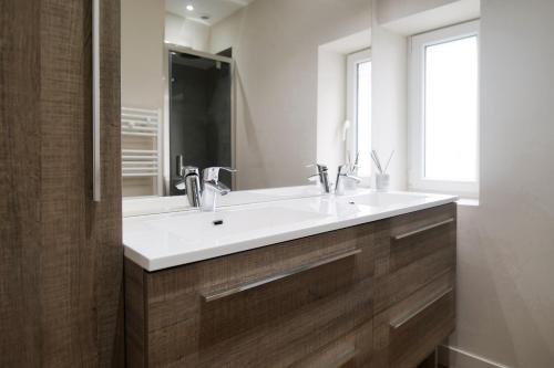 Un baño con un lavabo blanco y un espejo. en Appartement rénové idéalement situe dans le centre piéton des Sables d'Olonne, en Les Sables-dʼOlonne