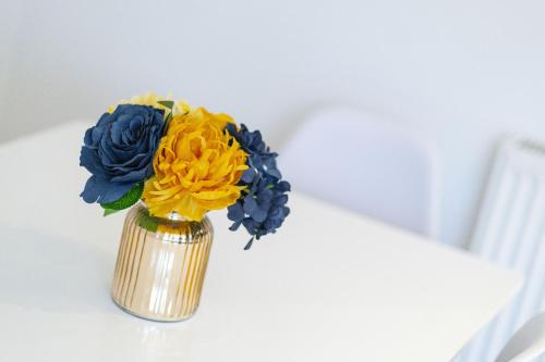 a vase filled with blue and yellow flowers on a table at Cross Road Apartment in Paisley