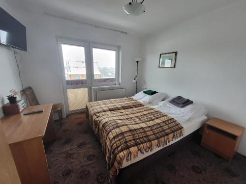 a bedroom with a bed and a desk and a window at Willa pod Babkami in Tylicz
