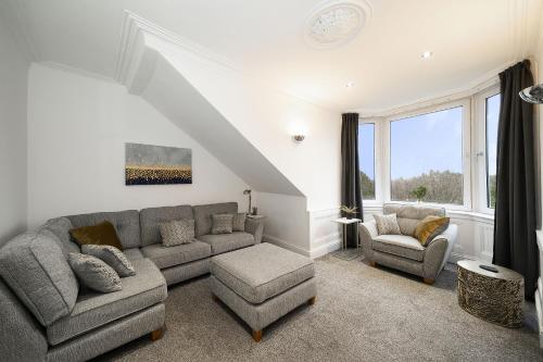 a living room with a couch and two chairs at Cross Road Apartment in Paisley