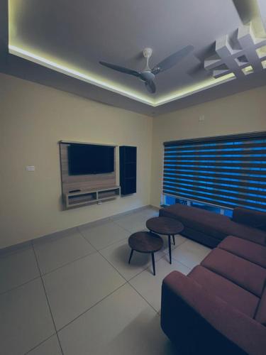 a living room with a couch and a tv at Azay Luxurious Apartment in Kalpetta
