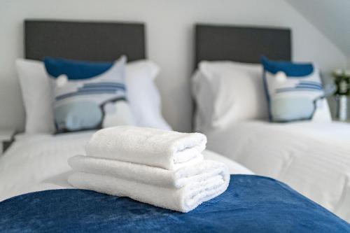 a pile of towels sitting on top of a bed at Cross Road Apartment in Paisley