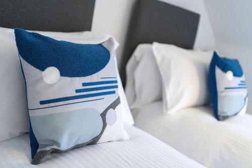 two white beds with blue and white pillows on them at Cross Road Apartment in Paisley