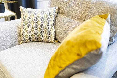 a yellow pillow sitting on top of a couch at Cross Road Apartment in Paisley