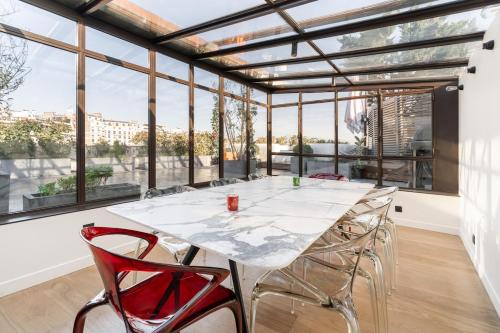 une grande salle en verre avec une table et des chaises dans l'établissement Splendide Apartment Rooftop Jacuzzi Tour Eiffel AC, à Paris
