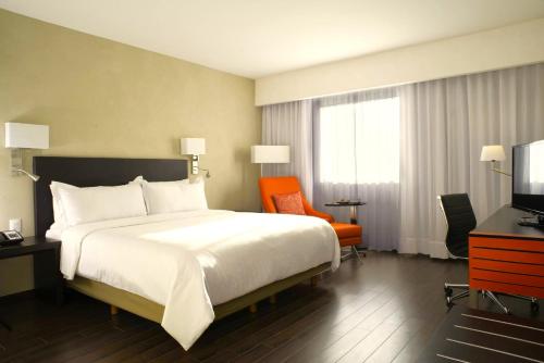 a hotel room with a large bed and a television at Hotel Opus Grand Toluca Aeropuerto in Toluca