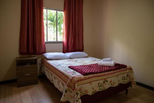 a bedroom with a bed and a window with red curtains at Sitio encantador e tranquilo com churrasq e Wi-fi in Marechal Floriano