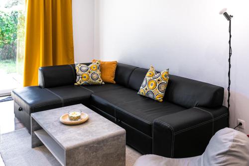 a black leather couch in a living room with a table at UBYTKO - Apartment in Blahová - Experience Rye Island in Blahová