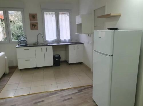 une cuisine avec des armoires blanches et un réfrigérateur blanc dans l'établissement Appartement moderne à Limeil-Brévannes de 56 m² avec jardin, à Limeil-Brévannes