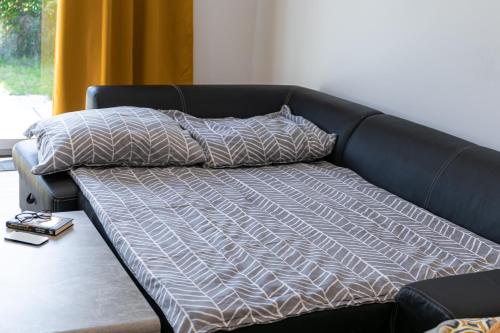 a black couch with a blanket and pillows on it at UBYTKO - Apartment in Blahová - Experience Rye Island in Blahová