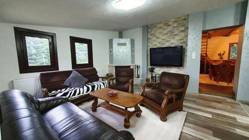 a living room with leather furniture and a television at Chata Panoráma Námestovo in Trstená