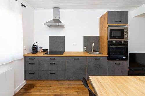 une cuisine avec des appareils en acier inoxydable et une table en bois dans l'établissement Belle Maison Nancy avec 3 chambres individuelles, à Nancy