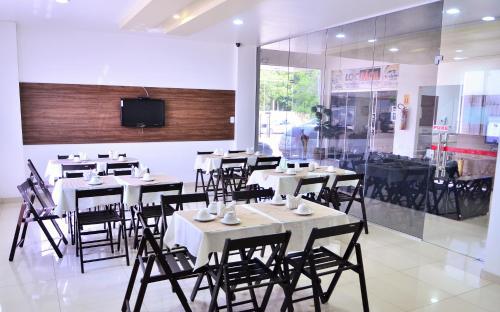 a restaurant with white tables and chairs and a tv at Hotel Norte in Macapá