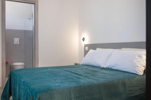 a bedroom with a bed with a green blanket on it at Villa Apeliote in Carovigno
