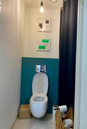 La salle de bains est pourvue de toilettes avec un mur bleu. dans l'établissement Appartement spacieux et lumineux de 67 m2, 2 balcons, à Saint-Ouen