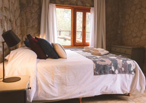 a bedroom with a bed with pillows and a window at Ruma Andina by DOT Cabana in Villa La Angostura