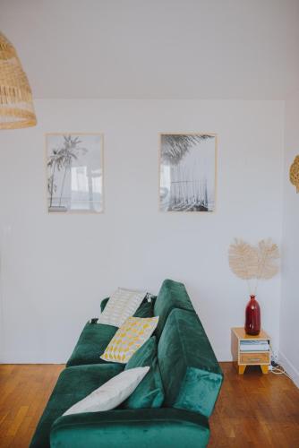 - un canapé vert dans le salon avec deux photos sur le mur dans l'établissement Le Côte Ouest - 2 Bedroom Apartment with Garage, à Dijon