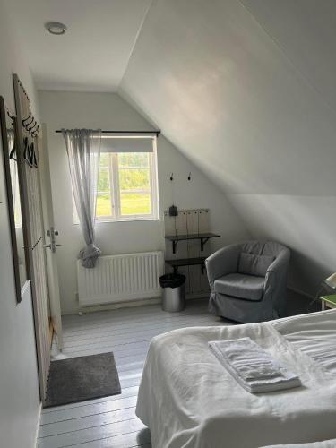 a bedroom with a bed and a chair and a window at Hallamölla Gård in Brösarp