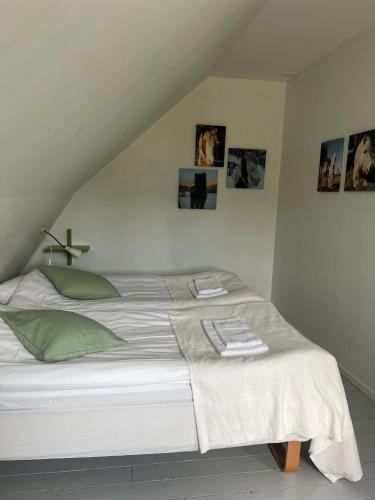a white bed in a room with pictures on the wall at Hallamölla Gård in Brösarp