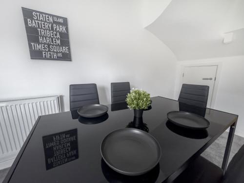 a black table with four chairs and a vase with flowers at Sleeps 8 with Garden and Pet Friendly in Ashford